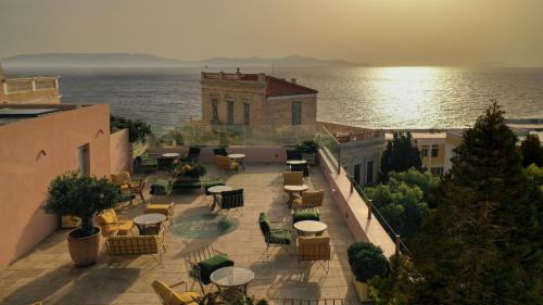 a patio with tables and chairs next to the water at Aristide Hotel - Small Luxury Hotels of the World in Ermoupoli