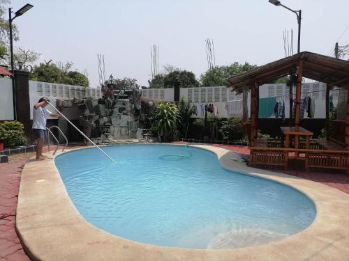 una persona está lavando una piscina con una manguera en GG Resort, en Dalumpinas Oeste