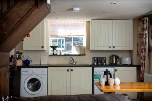 a kitchen with white cabinets and a washing machine at RB Contractor Stays - Celyn in Pwllheli