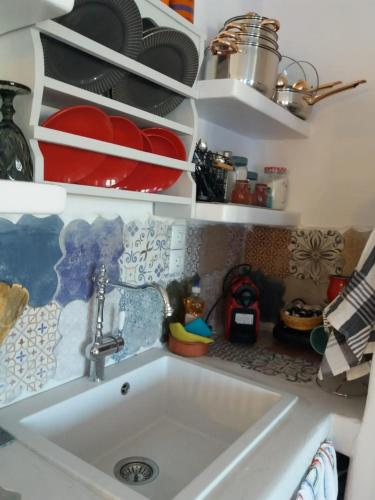 a kitchen with a sink and shelves with dishes at Spitaki-Kythnos in Loutra