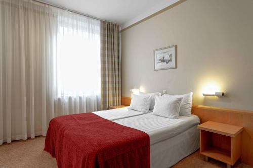 a bedroom with a bed with a red blanket and a window at Rixwell Viru Square Hotel in Tallinn