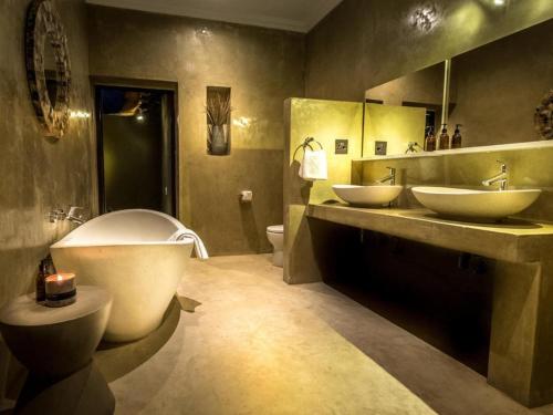 uma casa de banho com 2 lavatórios, uma banheira e um WC. em Bagatelle Kalahari Boutique Farmhouse Lodge em Mariental