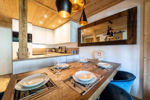 une cuisine avec une table en bois, des assiettes et des verres dans l'établissement Le Blue Velvet - IMMODREAMS - Avoriaz, à Avoriaz