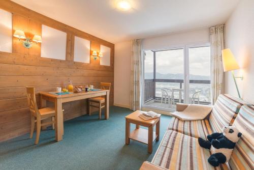 Cette chambre comprend un bureau, une table et un canapé. dans l'établissement Résidence Pierre & Vacances Le Pédrou, à Font-Romeu