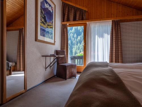 1 dormitorio con cama y ventana grande en Hôtel Cristal - Swiss Riders Lodge Grimentz, en Grimentz