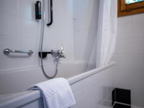 Baño blanco con ducha y toalla en Hôtel Cristal - Swiss Riders Lodge Grimentz en Grimentz