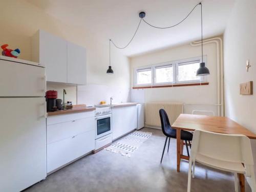 une cuisine avec une table et un réfrigérateur blanc dans l'établissement Courtine - Le calme au centre ville, à Strasbourg
