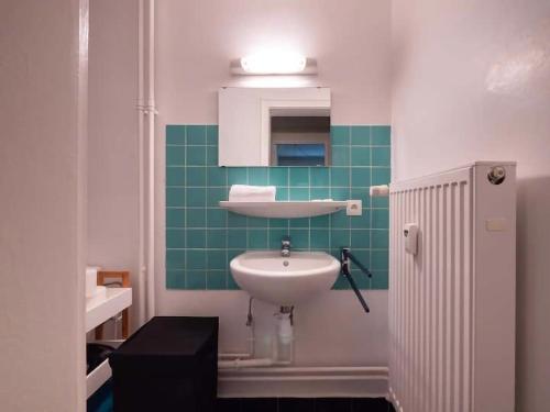 La salle de bains est pourvue d'un lavabo et d'un mur en carrelage vert. dans l'établissement Courtine - Le calme au centre ville, à Strasbourg
