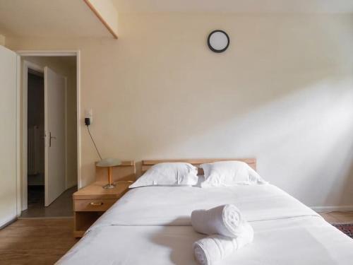 - un lit blanc avec des oreillers blancs et une horloge murale dans l'établissement Courtine - Le calme au centre ville, à Strasbourg