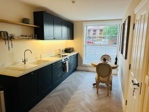 a kitchen with blue cabinets and a table and a window at Brand New Riverside Apartment in Christchurch