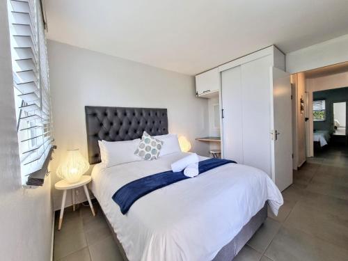a bedroom with a large white bed with a black headboard at Beautiful Chaka's Cove apartment in Ballito