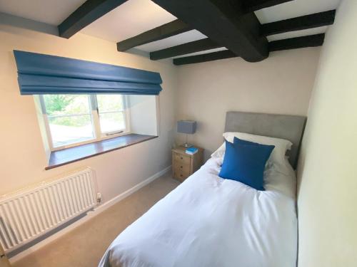 um quarto com uma cama com uma almofada azul e uma janela em Marrington Mill - Marrington Escapes em Chirbury