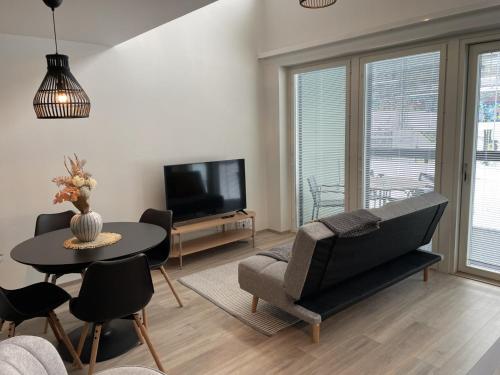 a living room with a couch and a table at Brand new loft apartment with glazed balcony in Tampere