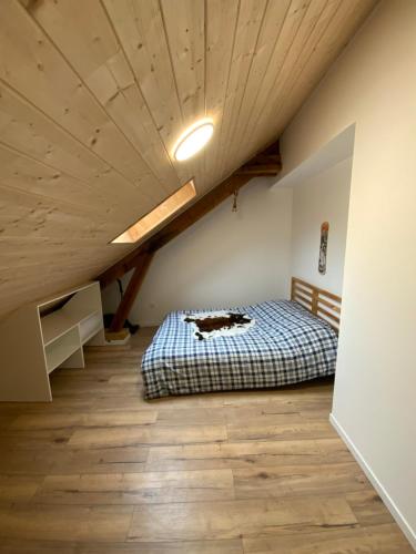 - une chambre mansardée avec un lit et un plafond en bois dans l'établissement APPARTEMENT 3 CHAMBRES A LA MONTAGNE, à Saint-Michel-de-Maurienne