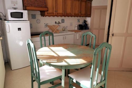 une cuisine avec une table et des chaises et un réfrigérateur blanc dans l'établissement 15 min du Puy Du Fou, Maison de bourg, 4/5 pers., à Pouzauges