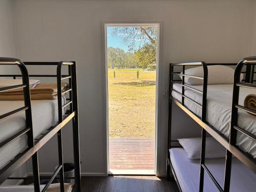 um quarto com beliches e uma porta para um campo em KangaROOMS Noosa Everglades YHA em Cootharaba