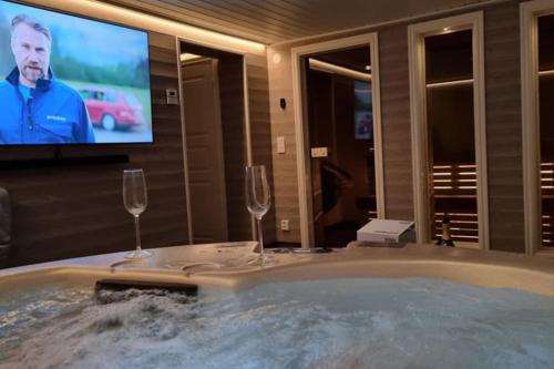 a bath tub with two wine glasses and a tv at Fantastisk Stuga i Hälsingland, Los! in Los