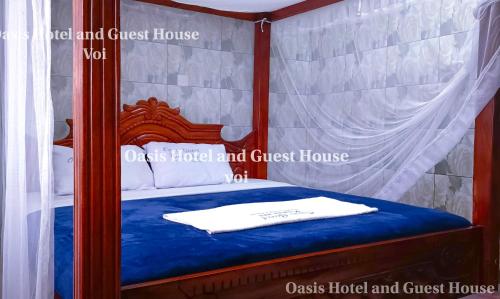 a bedroom with a canopy bed with a blue bedspread at Oasis Hotel and Guest House. Voi in Voi