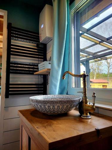 a bathroom sink on a wooden counter with a window at Dom Malarki in Mirosławiec