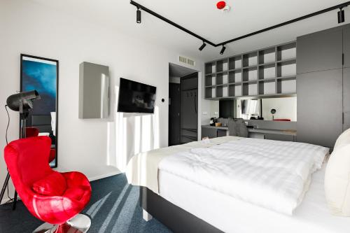 a bedroom with a white bed and a red chair at Hotel Historia Malomkert in Veszprém