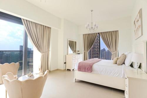 ein weißes Schlafzimmer mit einem weißen Bett und Fenstern in der Unterkunft HiGuests - Beautiful 2BR on 35th floor With Amazing City View in Dubai