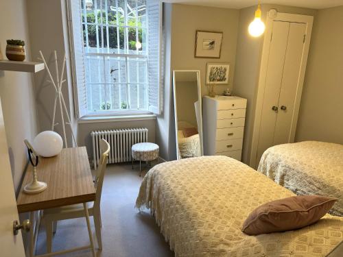 a bedroom with two beds and a table and a window at ALTIDO Vibrant 2 Bedroom Apartment in City Centre in Edinburgh