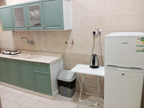 uma cozinha com armários verdes, um lavatório e um frigorífico em شقق الفتح الخاصة Al-Fateh Private Apartments em Medina