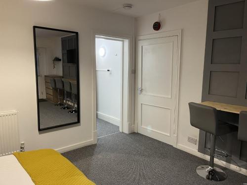 - une chambre avec un miroir, un lit et un bureau dans l'établissement The Cozy Apartment, à Gloucester