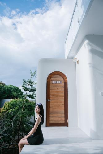 a woman sitting on a ledge in front of a door at Arabica Lodge (อาราบิก้า ลอดจ์) in Ban Huai Khai