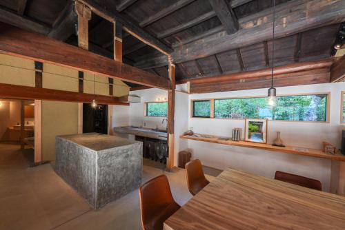 una cucina con soffitti in legno, tavolo e sedie di 奥明日香古民家一棟貸し宿 弥栄 Yasaka ad Asuka