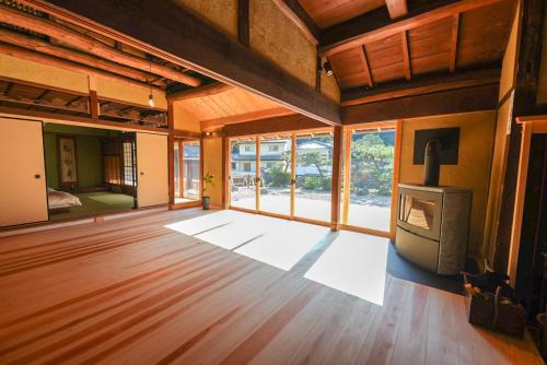 una sala de estar vacía con chimenea y suelo de madera. en 奥明日香古民家一棟貸し宿 弥栄 Yasaka, en Asuka