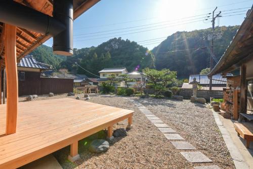 a wooden bench in a yard with mountains in the background at 奥明日香古民家一棟貸し宿 弥栄 Yasaka in Asuka