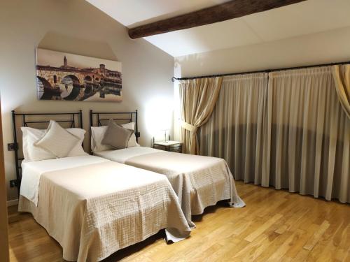 two beds in a hotel room with white sheets at Tenuta Albertini in Zevio