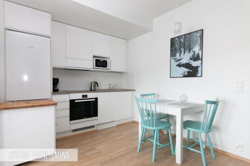 cocina con armarios blancos, mesa y sillas en Piriko Apartments en Rovaniemi