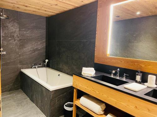 Un baño con lavabo, bañera y espejo. en RED LODGE, en Megève