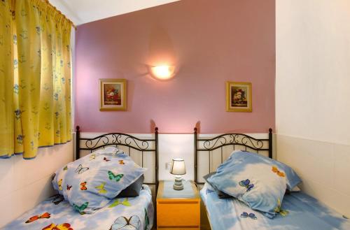 two twin beds in a room with pink walls at Haus Brigitte in Playa del Ingles
