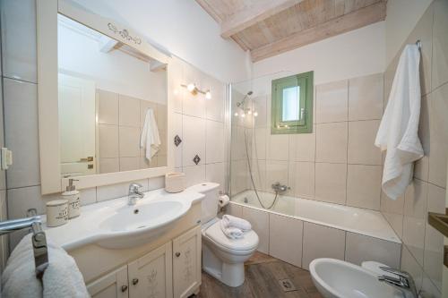 a bathroom with a sink and a toilet and a tub at ARCHITECT’S VILLA in Fiskardho