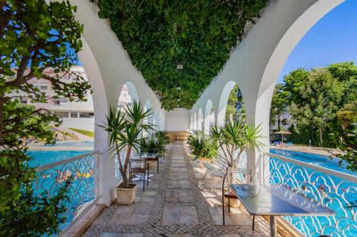 uma galeria com mesas e cadeiras ao lado de uma piscina em Clube Vilarosa em Portimão