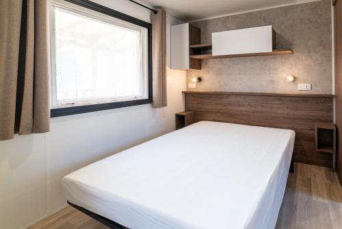 a bedroom with a white bed and a window at Camping siblu vue sur Canigou in Canet-en-Roussillon