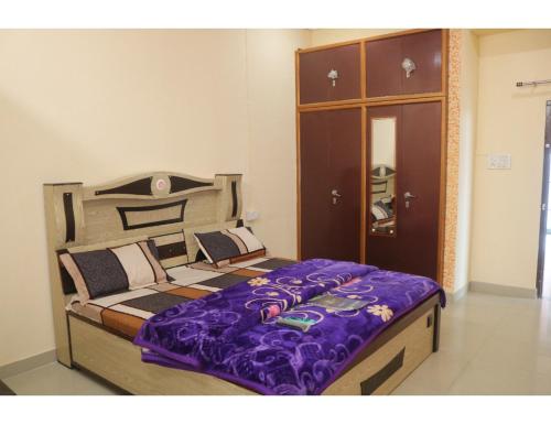 a bedroom with a bed with purple sheets and a cabinet at Hotel Poornima Palace, Fatehpur in Fatehpur