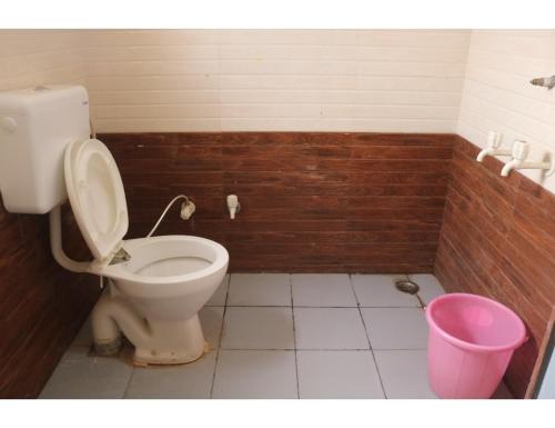 a bathroom with a toilet and a pink bucket at Hotel Poornima Palace, Fatehpur in Fatehpur