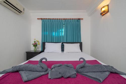暹粒的住宿－CENTRAL BACKPACKER，一间卧室配有一张带毛巾的粉红色毯子