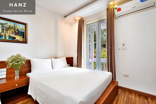 um quarto com uma cama branca e uma janela em HANZ Ami Central Hanoi em Hanói