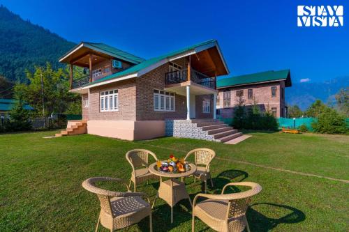 a house with a table and chairs in front of it at Qaraar - Preng by VEO - Part of StayVista in Srinagar