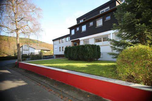 a black and white house with a red wall at Hotel Bechtel in Burbach