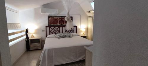 a bedroom with a white bed in a room at Villetta con giardino immersa nel verde a 150mt dal mare in Pula