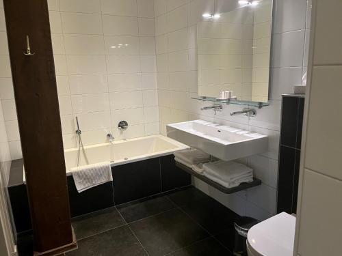een badkamer met een wastafel en een bad bij De Hiddinghhoeve in Onstwedde