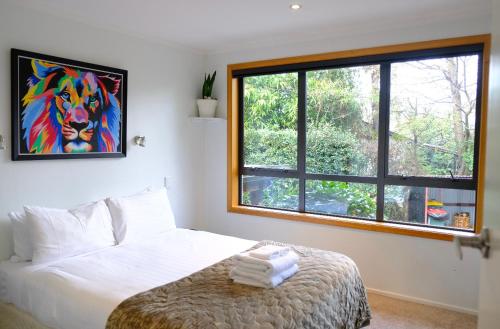 a bedroom with a bed with a painting on the wall at Wanaka Tree & Lake House in Wanaka