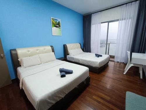 two beds in a room with blue walls and a desk at Bella Vista Silverscape Seaview Homestay in Melaka