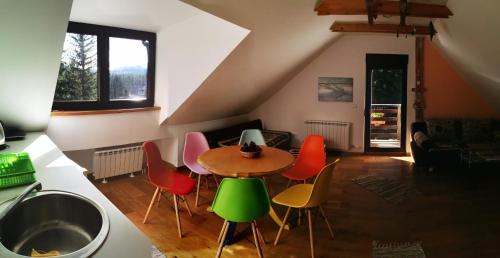 a living room with a table and colorful chairs at House Apartments Jahorinko in Jahorina